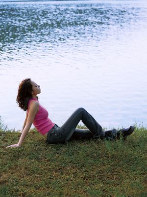 一位年轻女子在靠近水域的草地上
