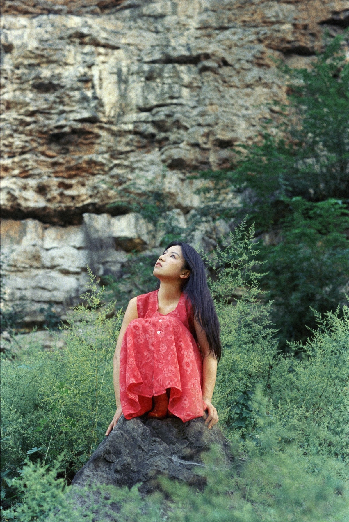 一位穿着红裙子的年轻女子坐在岩石上