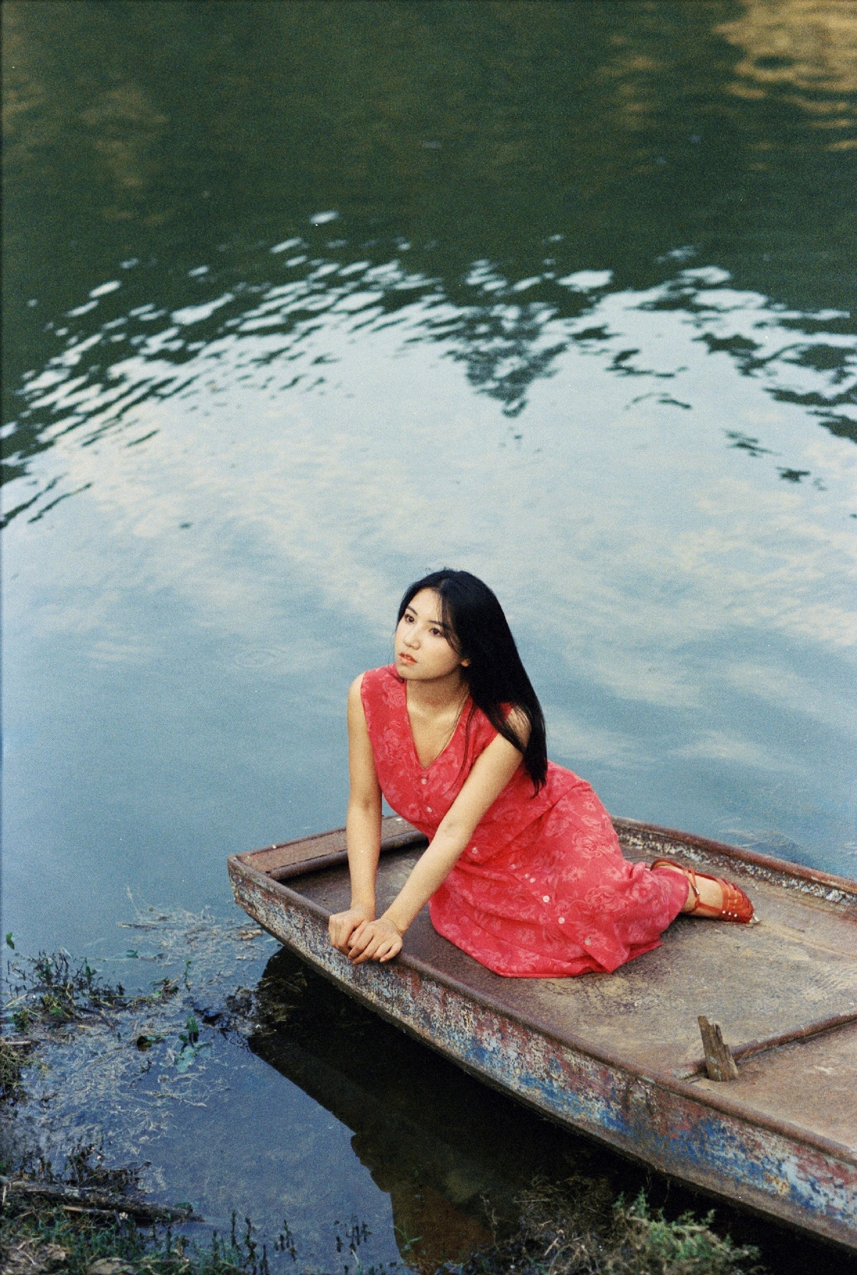 一位穿着红裙子的年轻女子坐在小船里