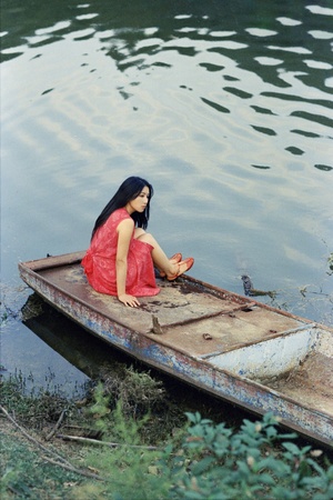 一位穿着红裙子的年轻女子坐在小船里
