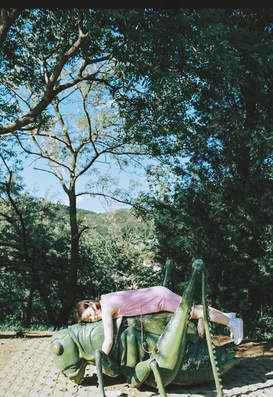 一个女人躺在公园的长椅上 上面躺着一只虫子的雕像