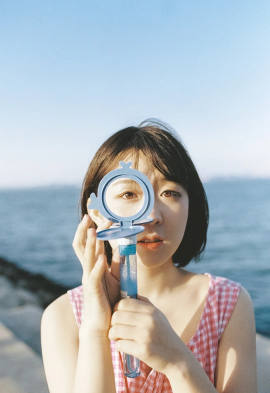 一个年轻的女人举着放大镜看着大海