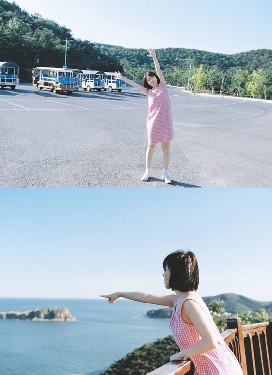 一个穿着粉色连衣裙的年轻女子站在长椅旁 伸出双臂