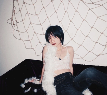 一个年轻女子坐在黑色沙发上 有一只白色狗。