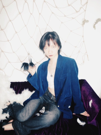 一个年轻女子坐在沙发上 旁边有一只白色狗和一只白色贵宾犬。