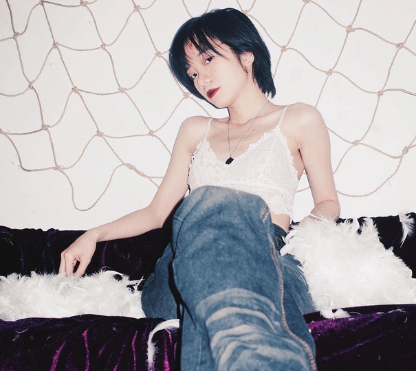 一个年轻女子坐在沙发上 床上有只白狗和一只猫。