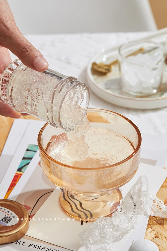 一个人正在往桌子上的一杯水中倒盐 旁边还有其他餐具和食材。