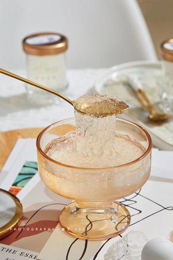 一个带有食物的表格 一个勺子在往玻璃杯里倒糖。