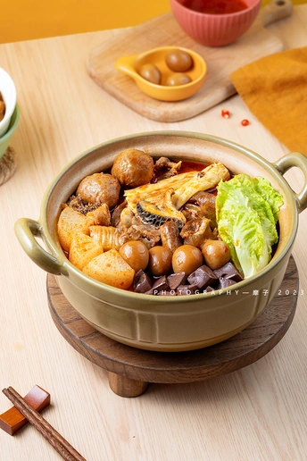 一碗汤里有肉和蔬菜 放在木桌上 筷子上夹着