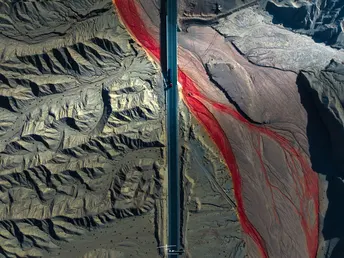 杆子上有一个红色和白色的标志 旁边是一座山。