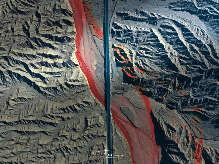 一架飞机在巨大的山脉上空飞行 上面有一个红色的旗帜。