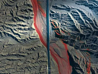 一架飞机在巨大的山脉上空飞行 上面有一个红色的旗帜。