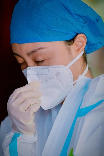 戴着口罩和蓝色长袍、戴着手套的女医生或外科医生