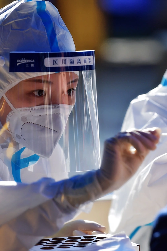 一名身穿医疗服、戴着口罩的妇女在实验室的笔记本电脑前工作