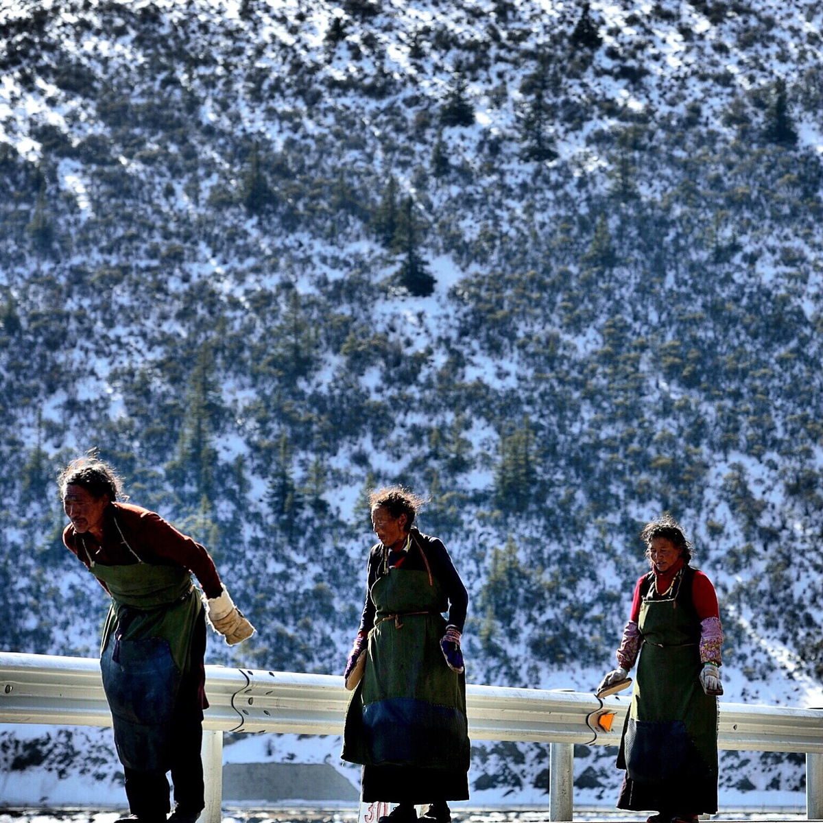 人们站在雪地里的桥上 背景是一座雪山