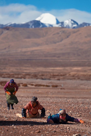 一位妇女和孩子在一片贫瘠的土地上玩耍 背景是群山