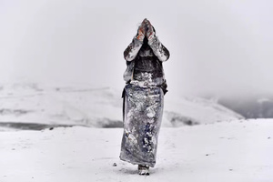 一个穿着连衣裙的人在雪山上的雪地里行走