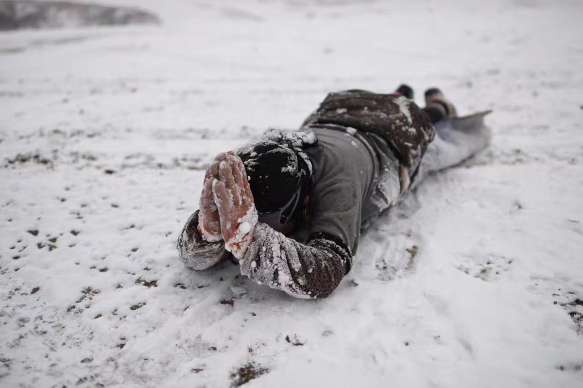 一个人滑雪下山时双手高举躺在雪地里
