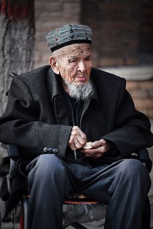 一个老人戴着帽子坐在长凳上