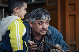 一个老人手里拿着一个带有锤子的木棍 一个小男孩站在他旁边。