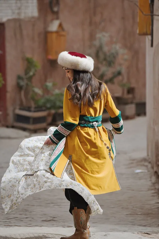 一个穿着黄色裙子和帽子的小女孩走在街上。