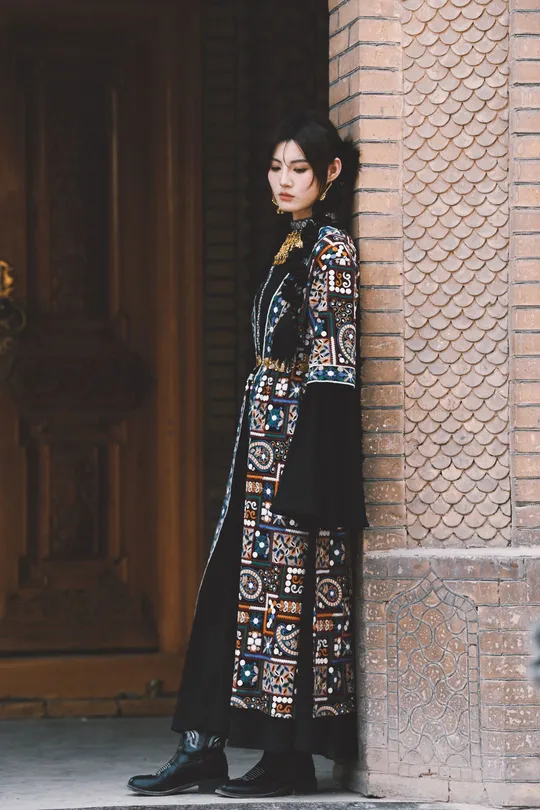 一位穿着黑色连衣裙的长款外套的模特