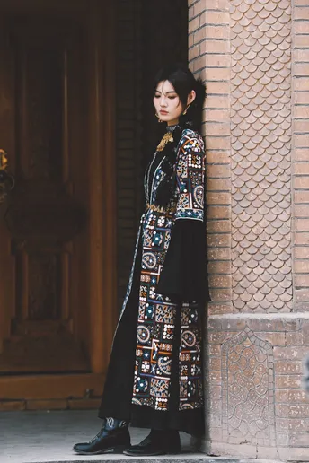 一位穿着黑色连衣裙的长款外套的模特