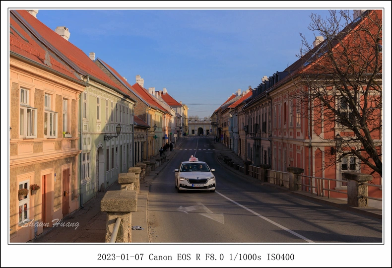 一辆白色汽车驶过一条被老建筑环绕的街道