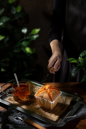 一个人用刀在一个小盘子里切一杯茶 在桌子上的托盘上切一些纸杯蛋糕
