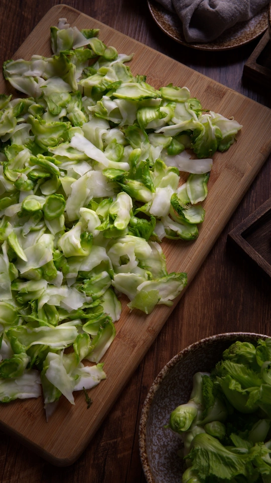 一个木制的菜板上有生菜和一盆西兰花在桌子上