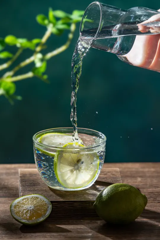 倒入带有柠檬和黄柠檬的玻璃杯中的水