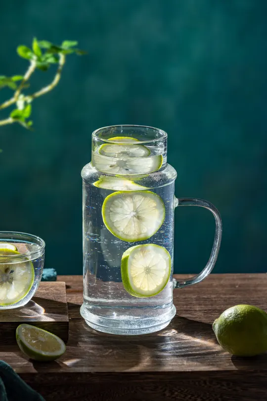 一杯带有柠檬和青柠的水 放在木桌上。