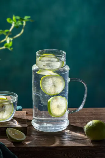 一杯带有柠檬和青柠的水 放在木桌上。