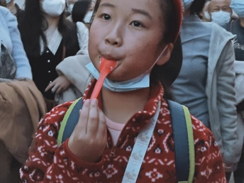 一个戴红橡胶圈的女孩站在人群前 手里拿着一个人。