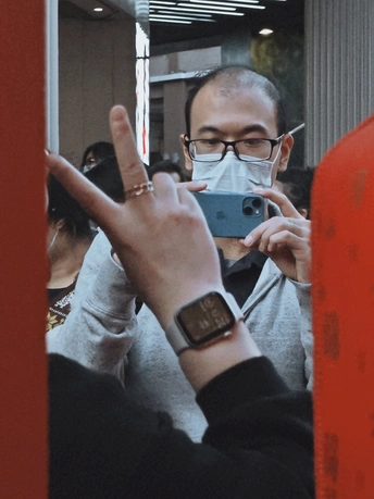 一个戴面罩和眼镜的男子举起他的手机用手指自拍镜子