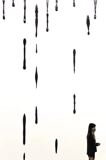 一个人拿着黑伞在看一个有钟表的墙