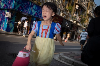 一个小女孩穿着粉红色裙子走在街上