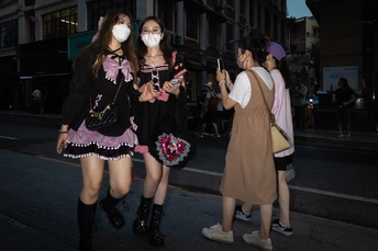 年轻女性在香港中国于2013年5月8日晚上戴着口罩走下街道。人们已经戴了几年的口罩照片由<人名>/ 