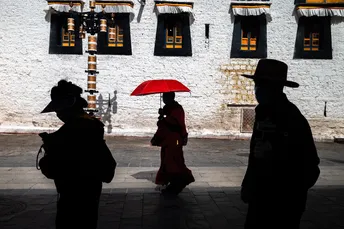 一些人拿着红伞站在一栋建筑前