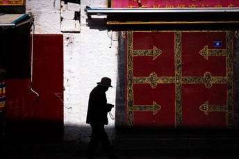 一个戴帽子的男人的剪影走过一扇红门