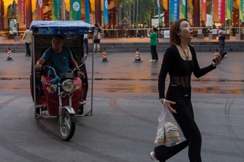 一位妇女骑自行车在人们旁边的一条街道上