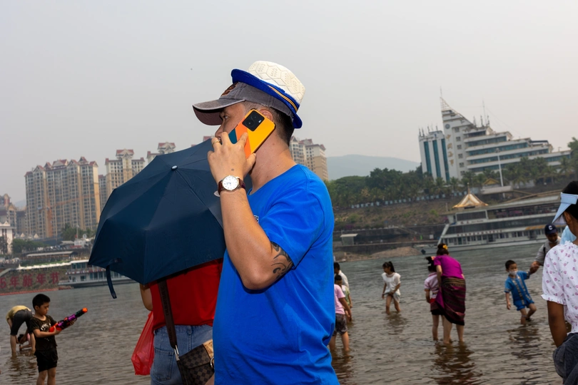 一个穿着蓝色衬衫和帽子的人在水中与背景中的人们通话