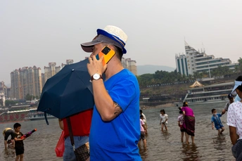 一个穿着蓝色衬衫和帽子的人在水中与背景中的人们通话