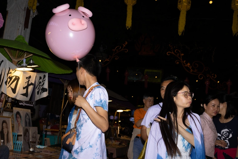 一个年轻女孩拿着粉红色气球走在街上