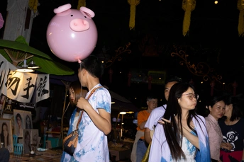 一个年轻女孩拿着粉红色气球走在街上