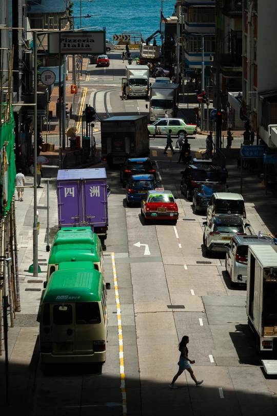 行人走在面对海洋的城市街道上 街道上充满了交通和绿色的汽车。