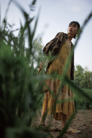 一个穿着黄色连衣裙的年轻女子站在一片高高的草地上