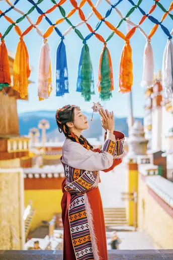 一位穿着传统服装的年轻女子在寺庙里从一个杯子喝水。