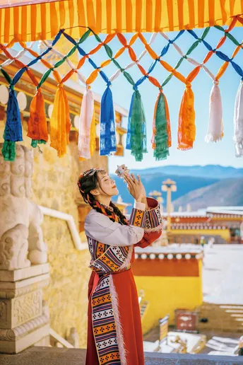一位身着传统服装的年轻女子站在一座寺庙外面。
