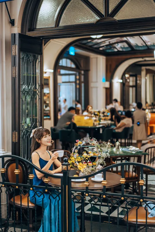 一个女孩坐在餐厅的桌子旁 旁边站着一个妇女。